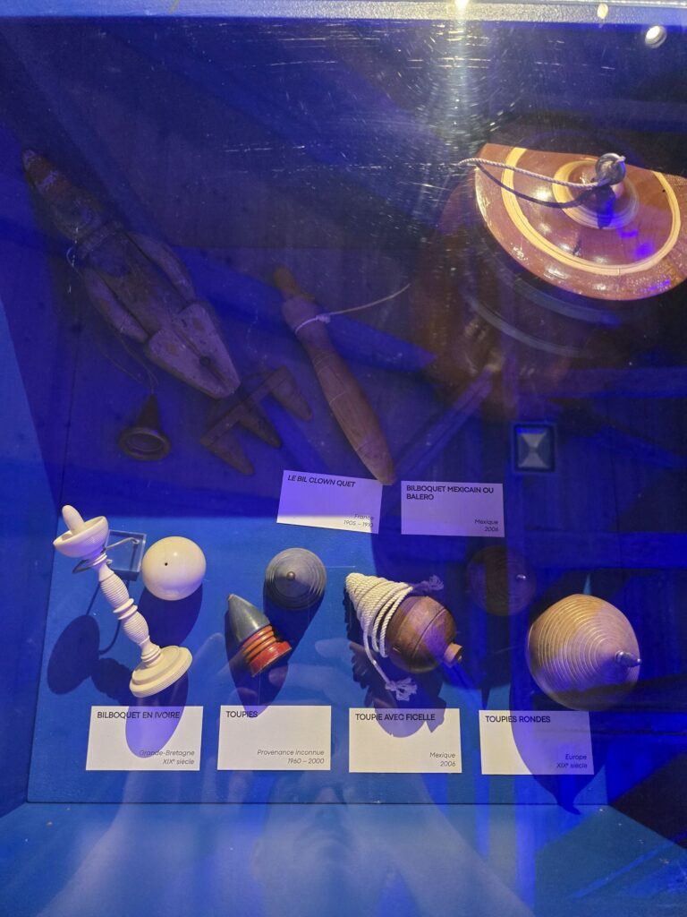 Collection de bilboquets et toupies exposés dans un musée du jeu